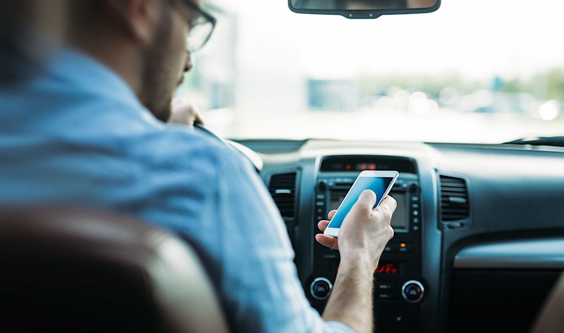 Gentleman texting on his phone while driving, distracted while driving, distracted driving in Pennsylvania.