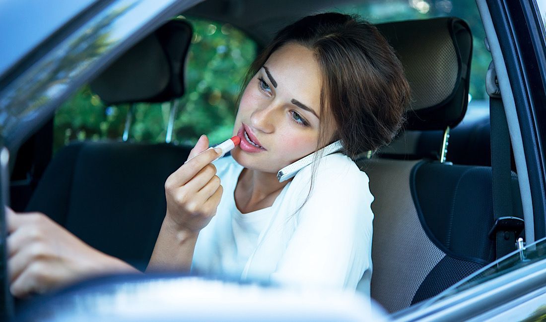 Woman applying lipstick and talking on the phone while driving, distracted driving in Pennsylvania