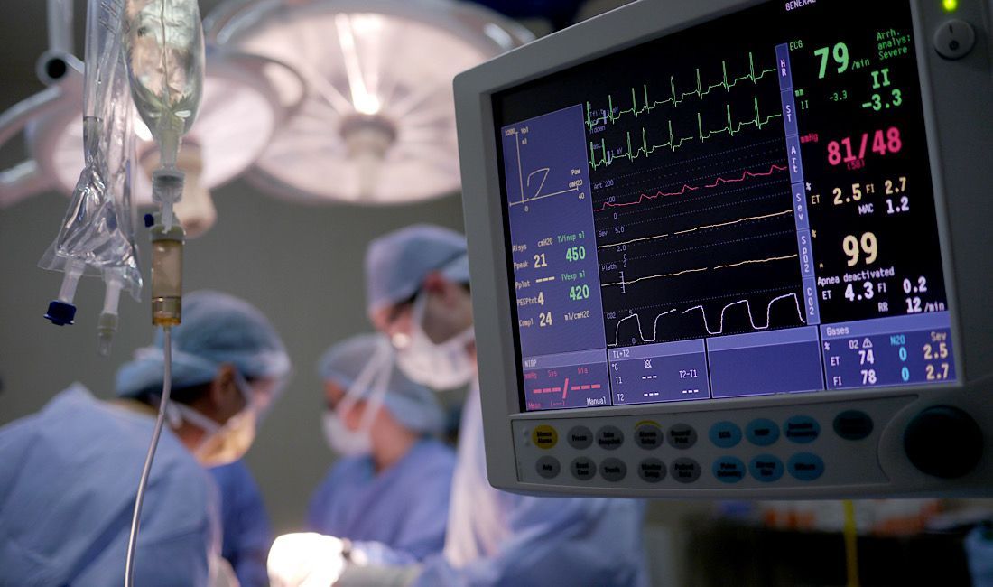 Heart monitor in the operating room next to a surgeon and two nurse technicians in Pittsburgh, PA.