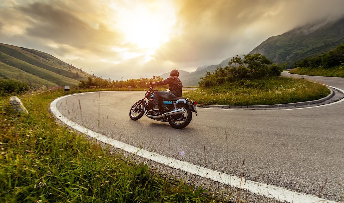 Man on a motorcycle rounding the corner of a mountain in summer weather in Pennsylvania.