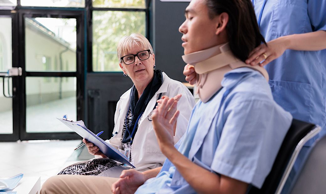 Traumatologist doctor and nurse helping patient to take off cervical neck collar, young patient receiving medical support