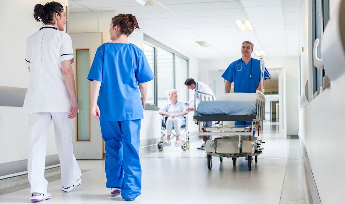 Nurse, doctor, patient walking in hospital in hallway