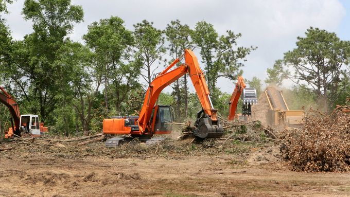 A group of construction vehicles are working on a dirt field.