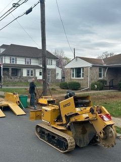 A yellow tractor is parked on the side of the road in front of a house.