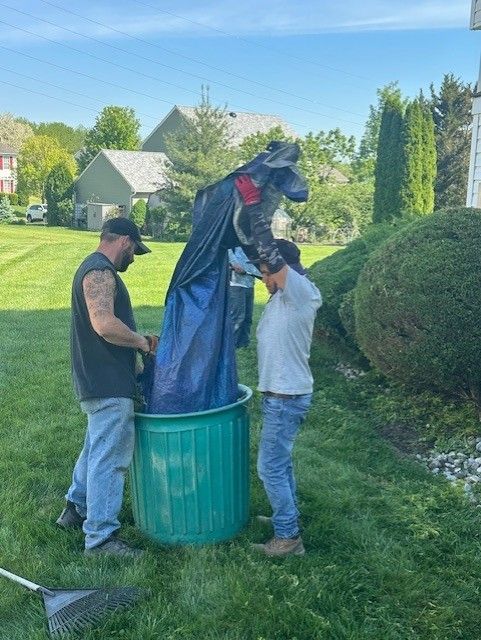 Two men are working on a statue in a trash can.