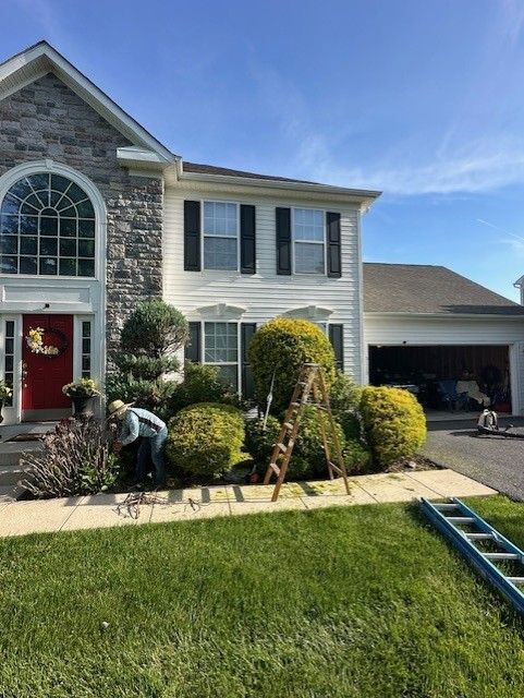 A man is standing in front of a house with a ladder in front of it.