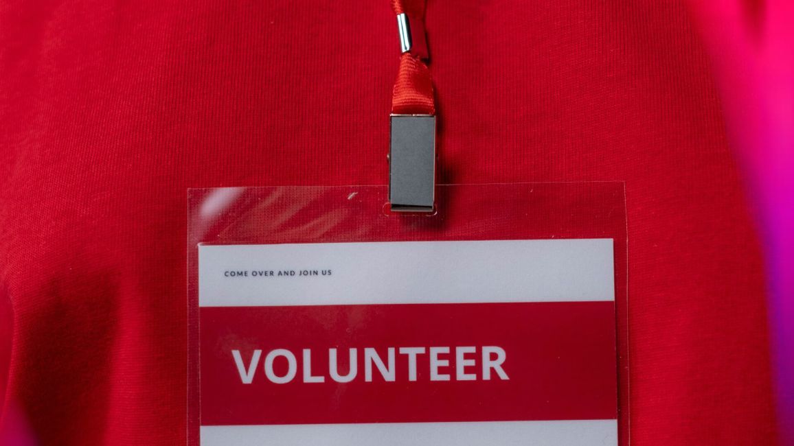 a person wearing a red shirt and a volunteer name tag .