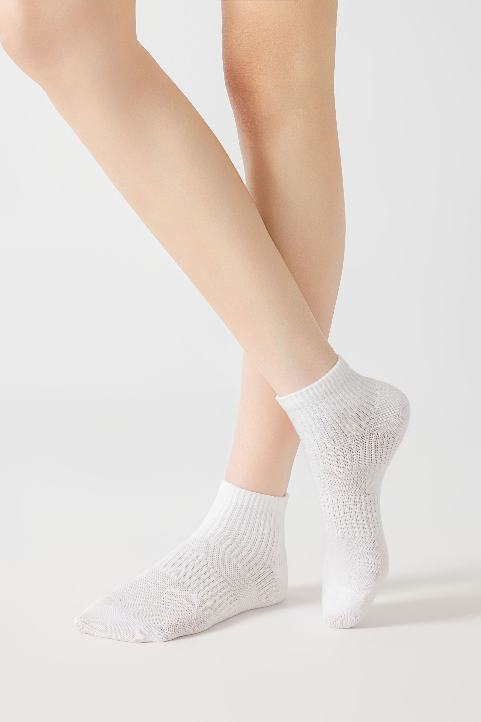 Person wearing white lace ankle socks; legs crossed, standing.