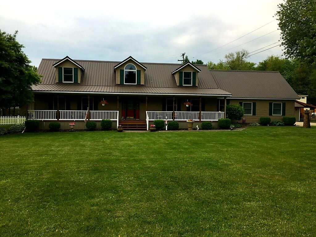 Green metal roof  with grasses in front yard— Croswell, MI — Parraghi Roofing & Sheet Metal, LLC