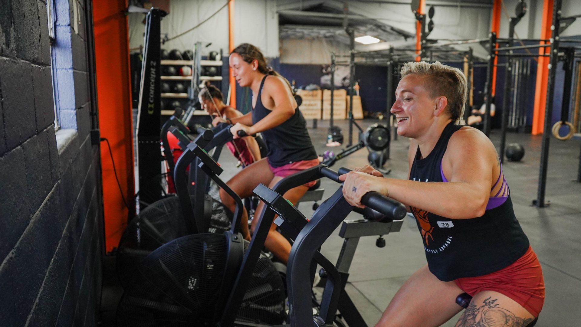 Two women are riding exercise bikes in a gym.