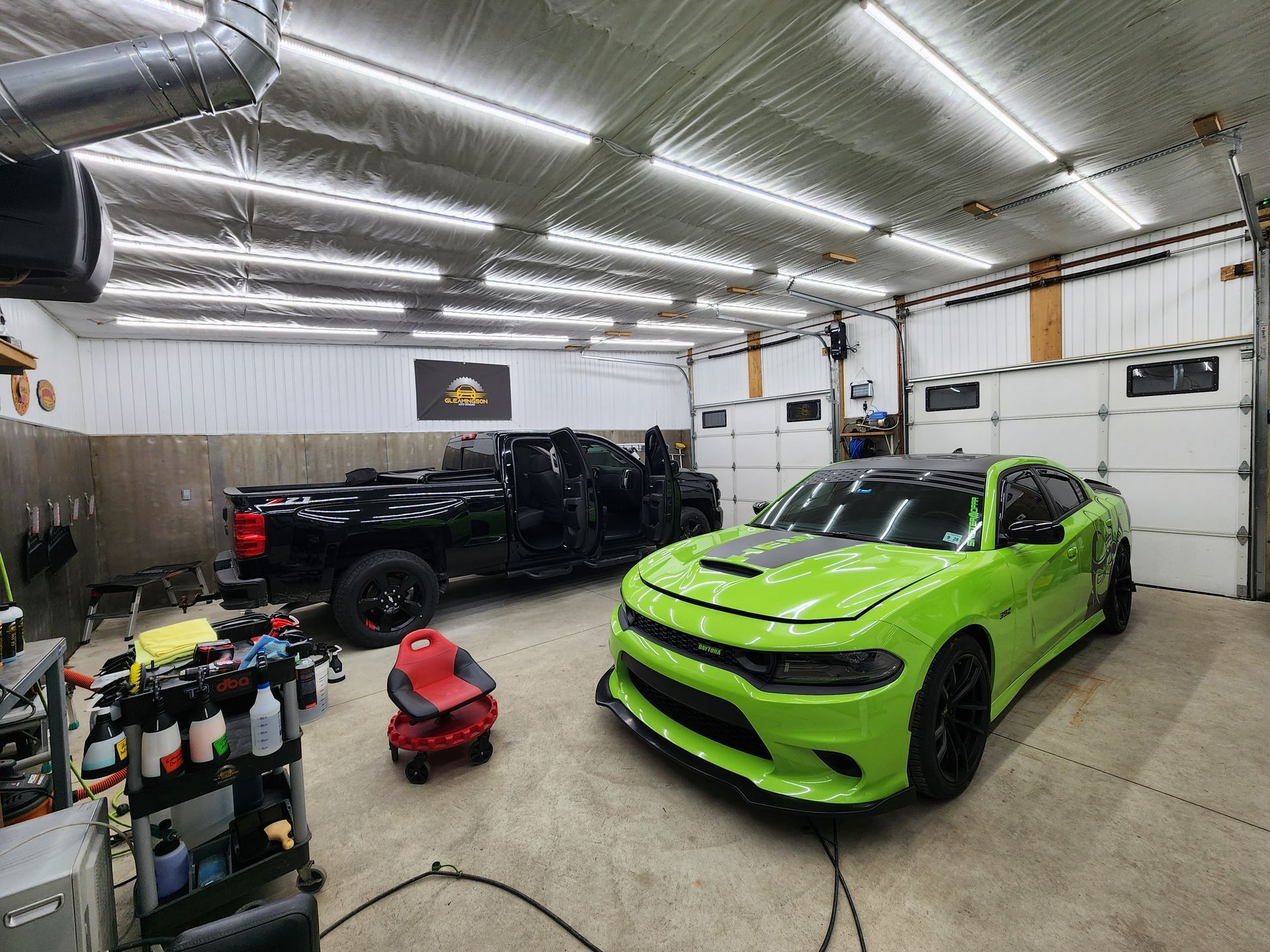 Black Dodge Charger on a winding road with yellow fog lights, blue headlights, and a forest backdrop.