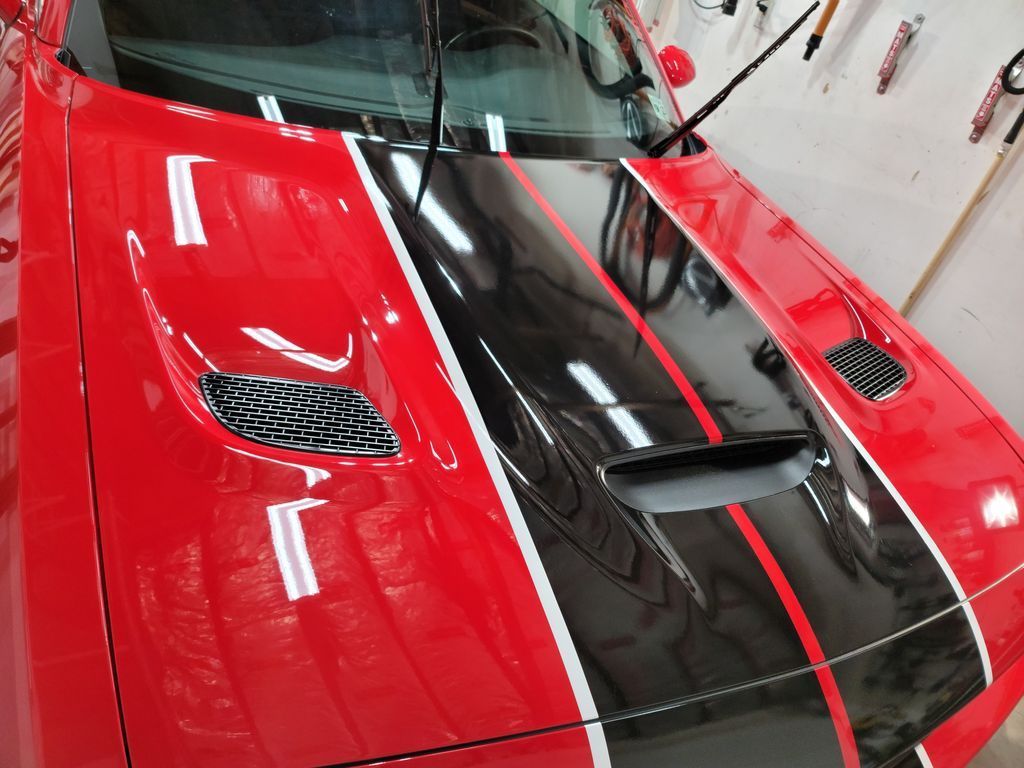 Red car hood with black racing stripes and air vents.