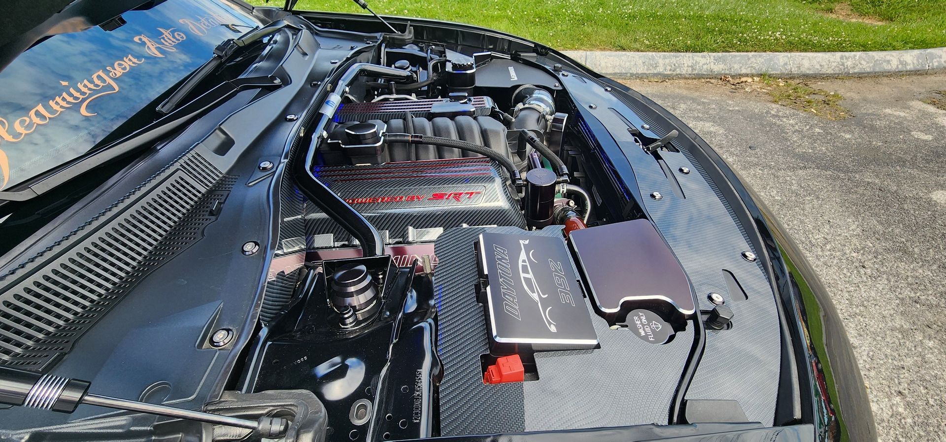 Black car engine with a custom engine bay, parked outdoors.