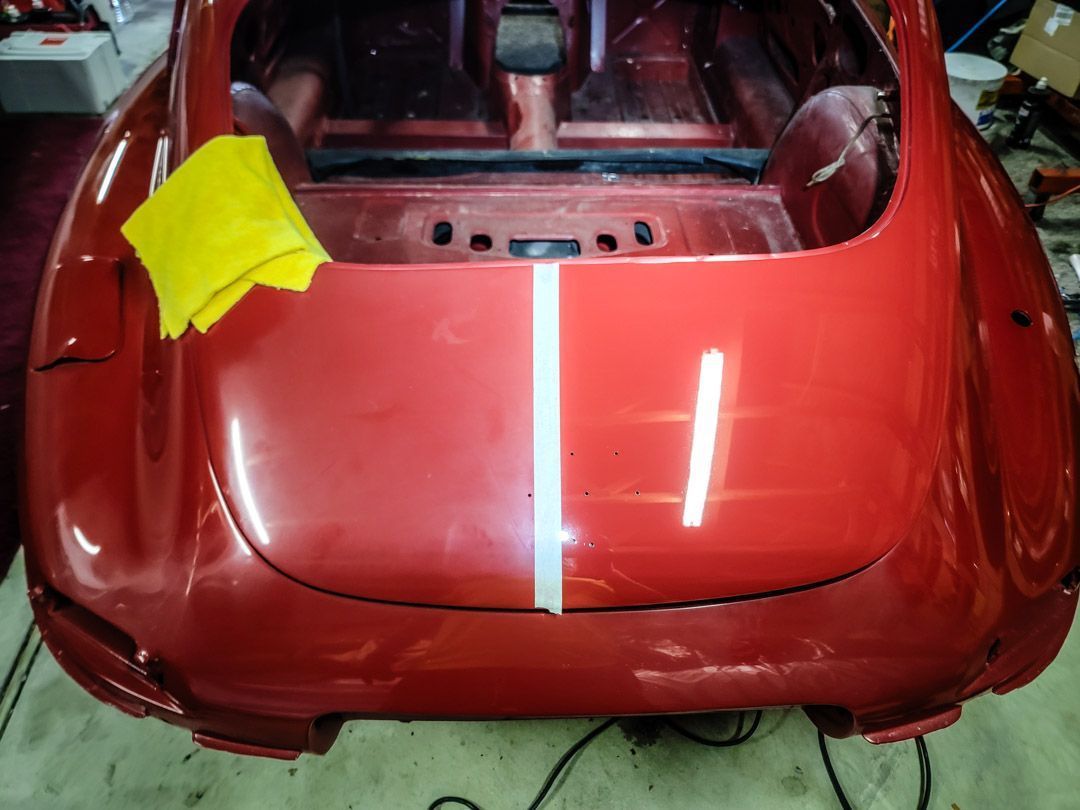 Red car rear with polished right side, unpolished left, yellow cloth.