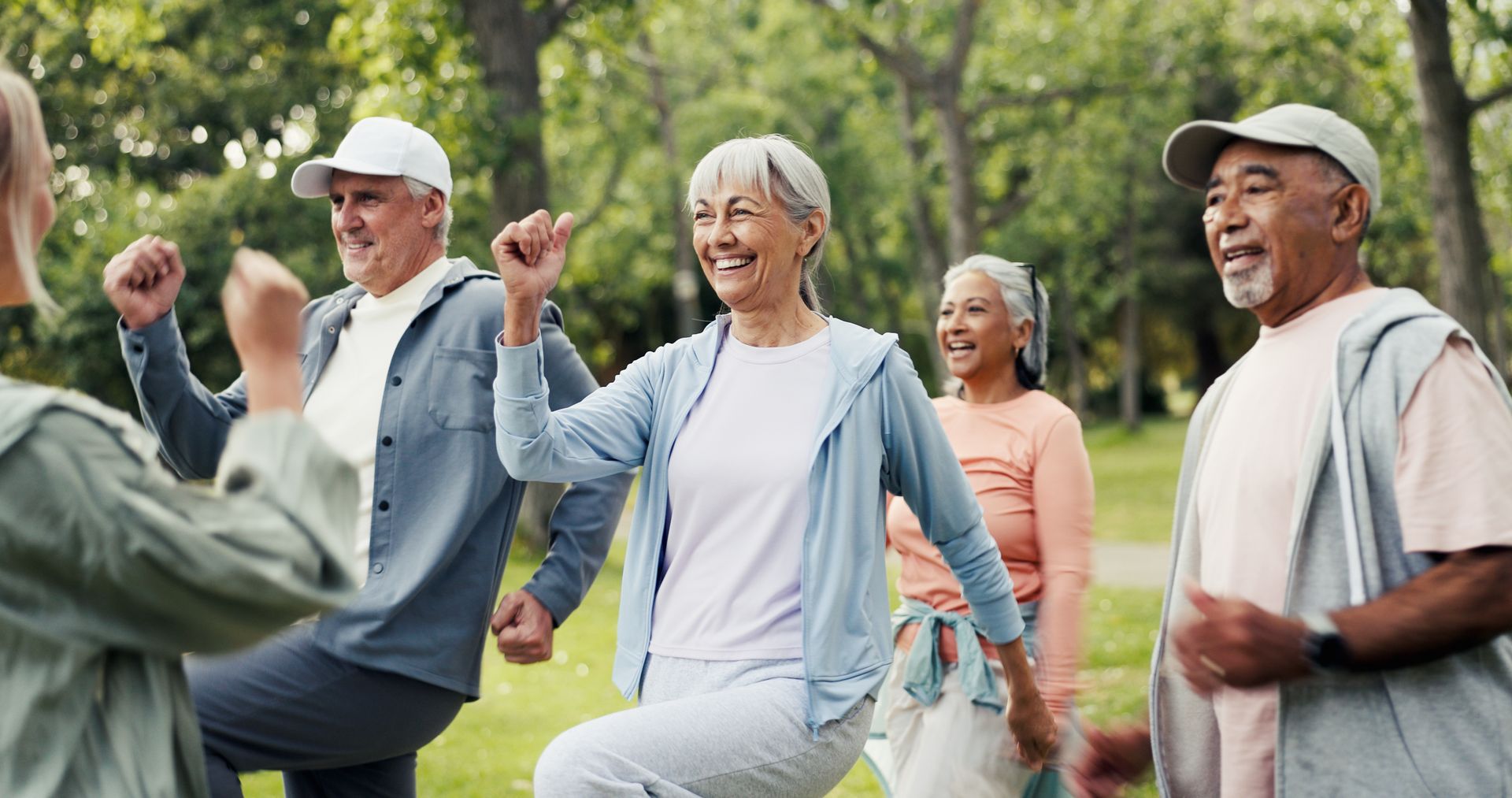 People exercising together in a park, smiling and lifting their knees during a group fitness session