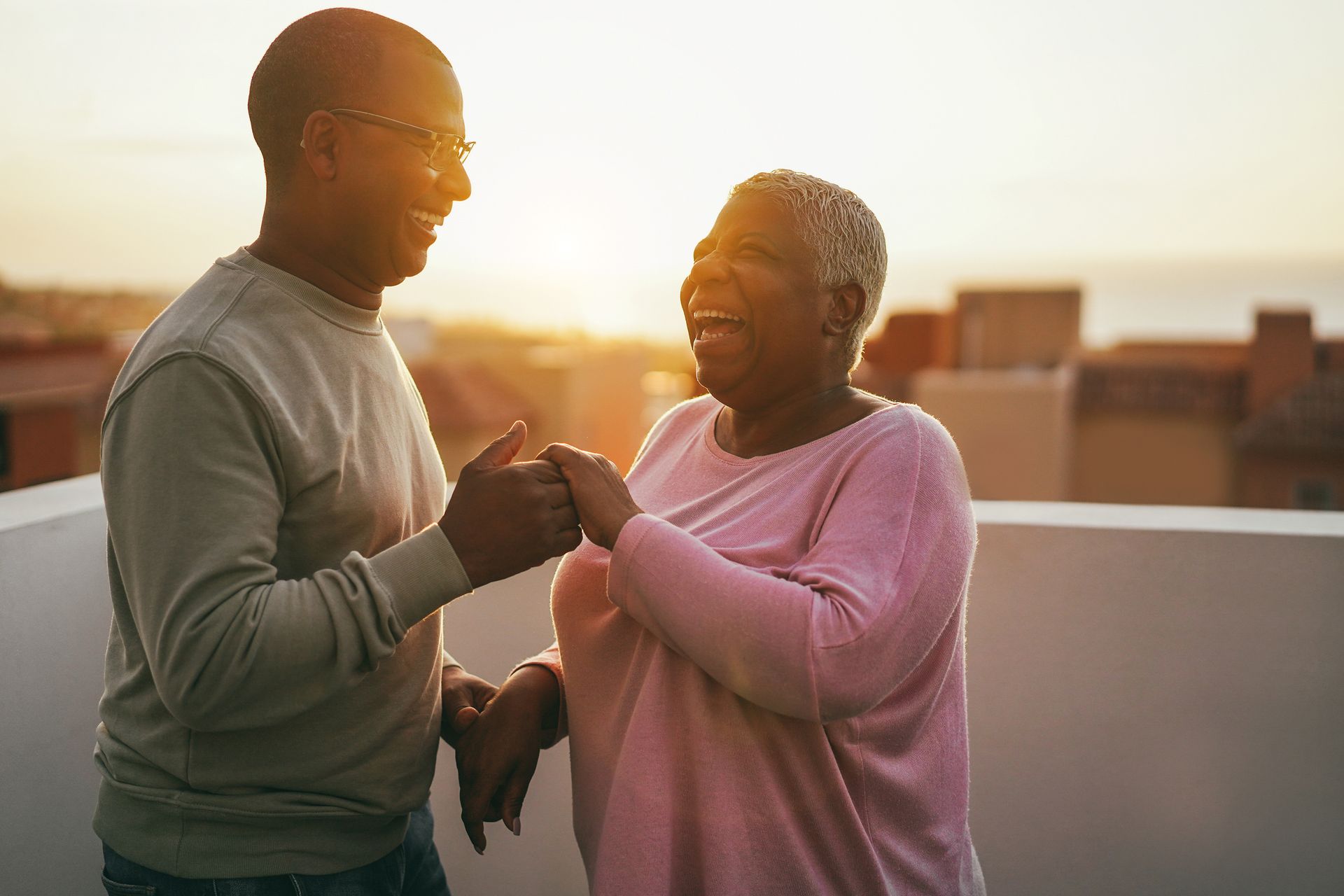 Two people smiling and touching fists on a rooftop at sunset