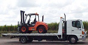 A Tow Truck Is Carrying A Forklift On The Back Of It — Day & Night Towing & Transport In Condon, QLD