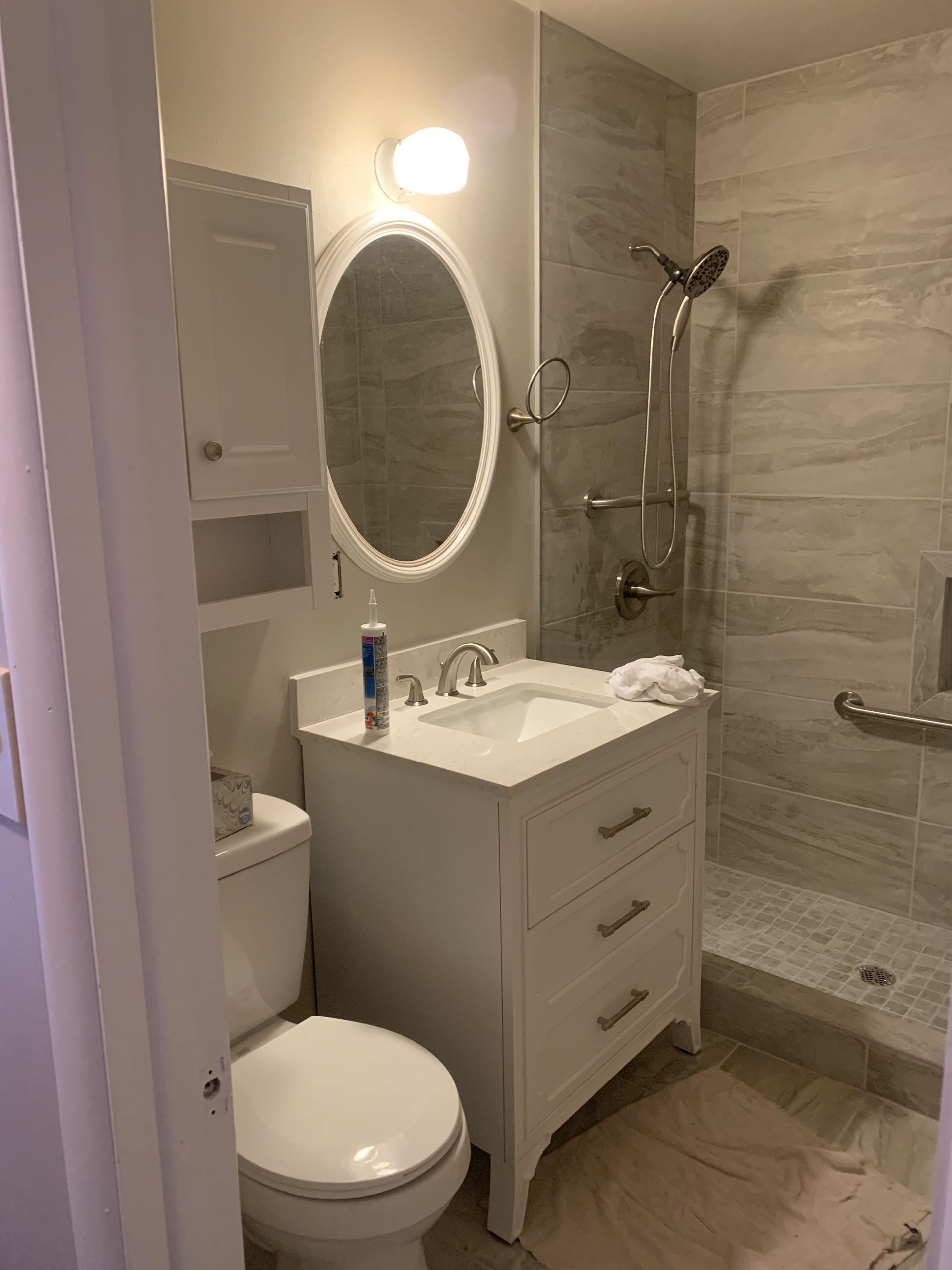 A bathroom with a toilet , sink , mirror and shower.