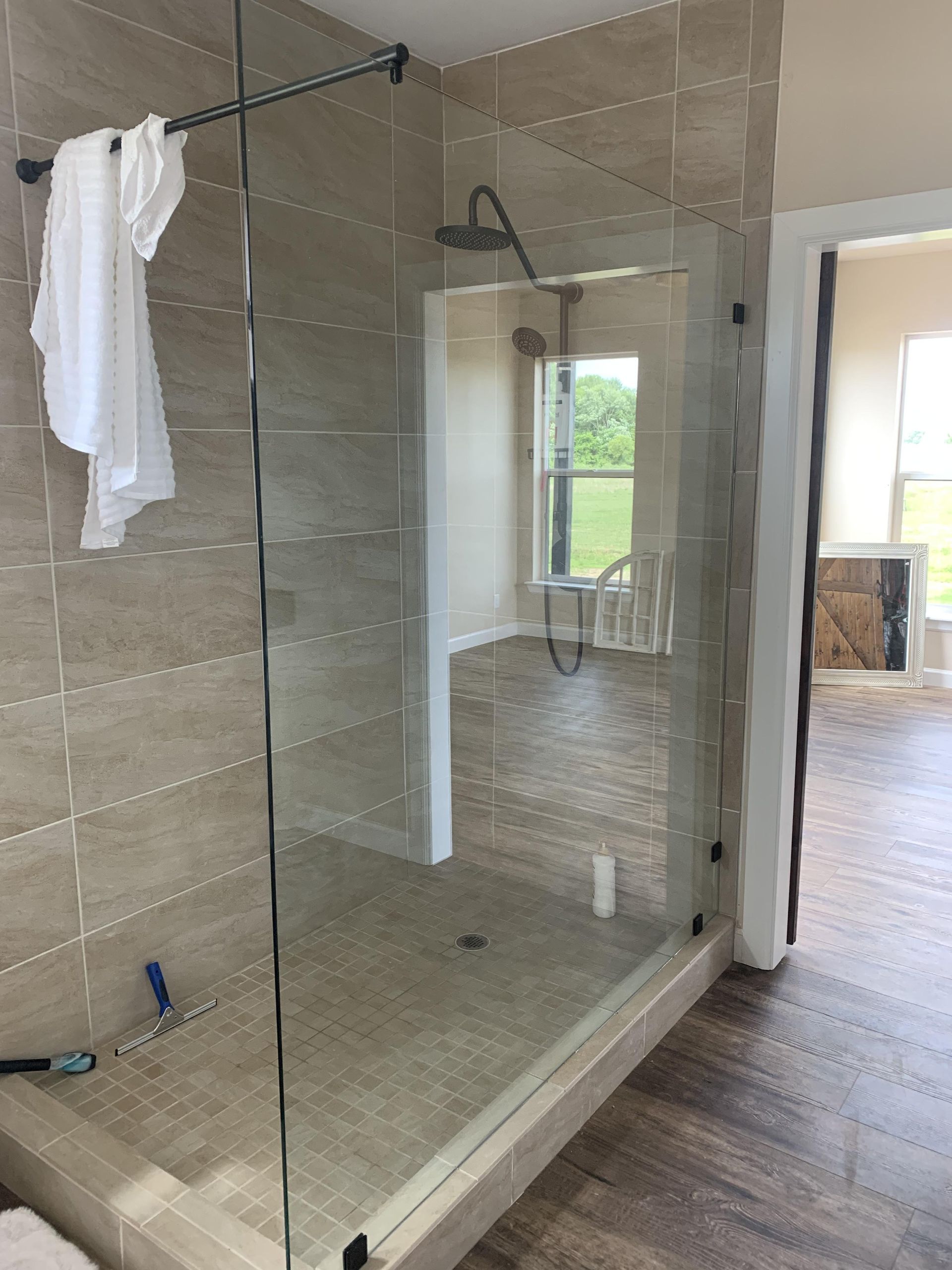 A bathroom with a walk in shower and a towel hanging on the wall.