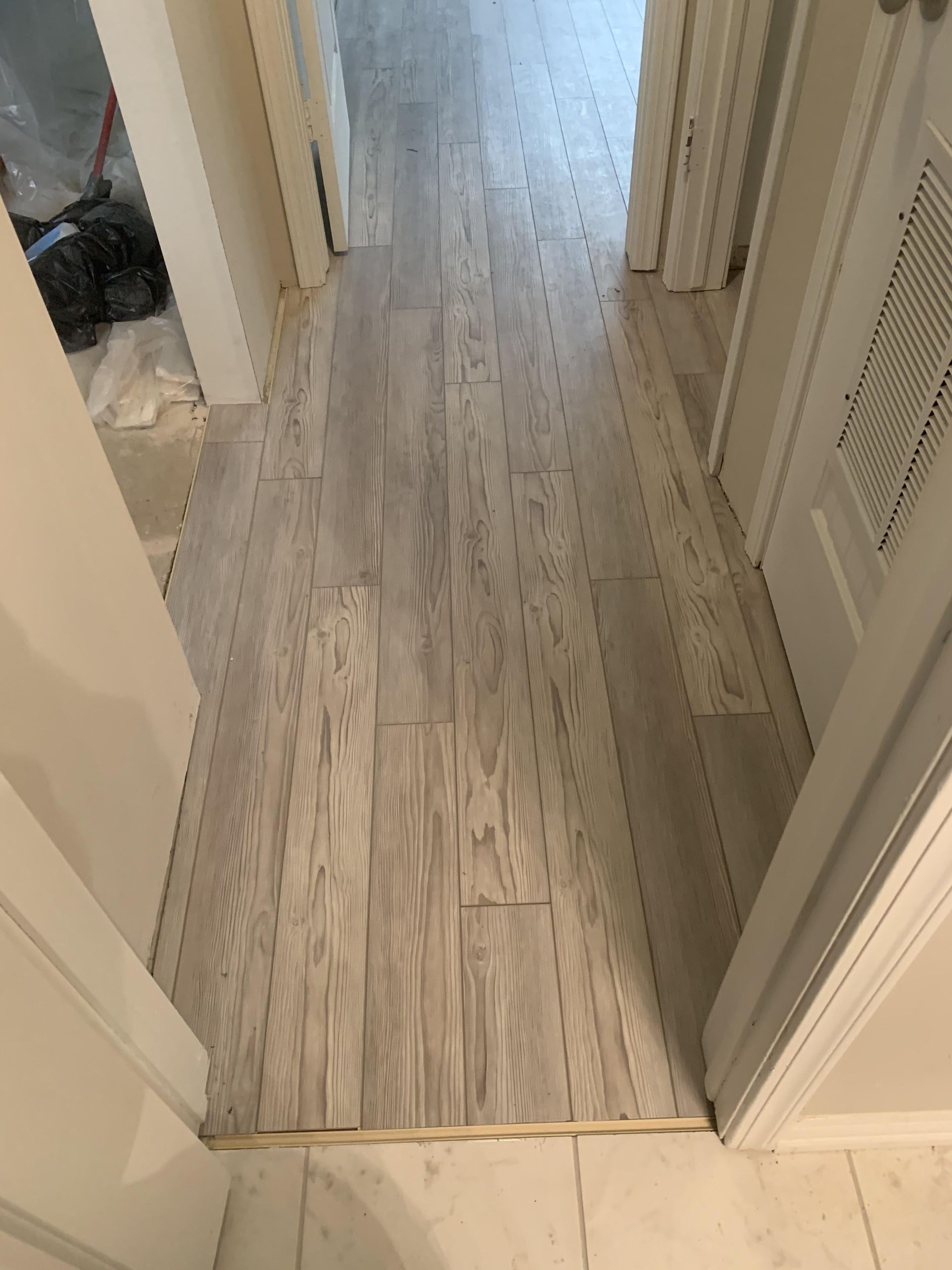 A hallway with a white tile floor and white doors.