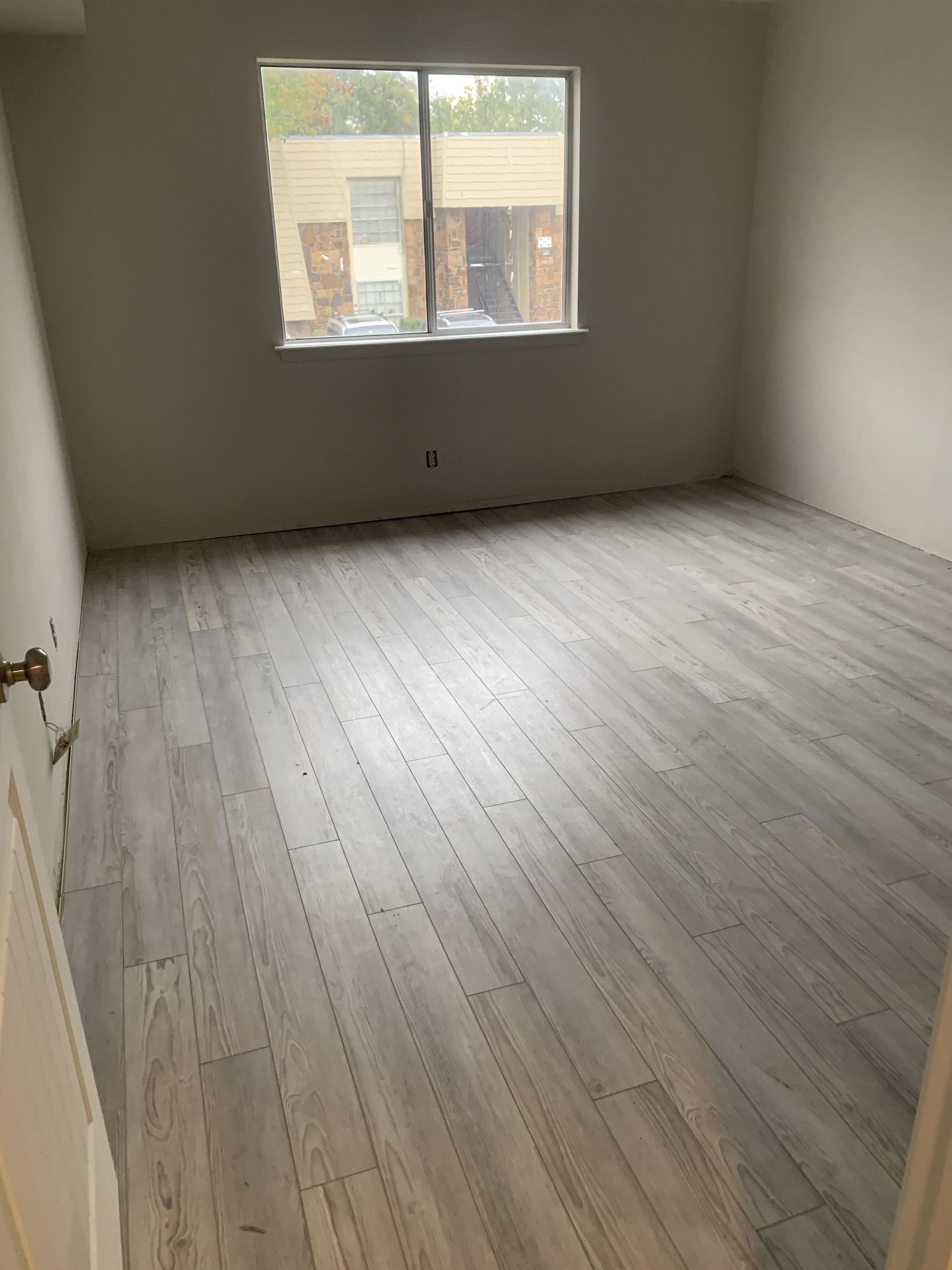 An empty room with hardwood floors and a window.