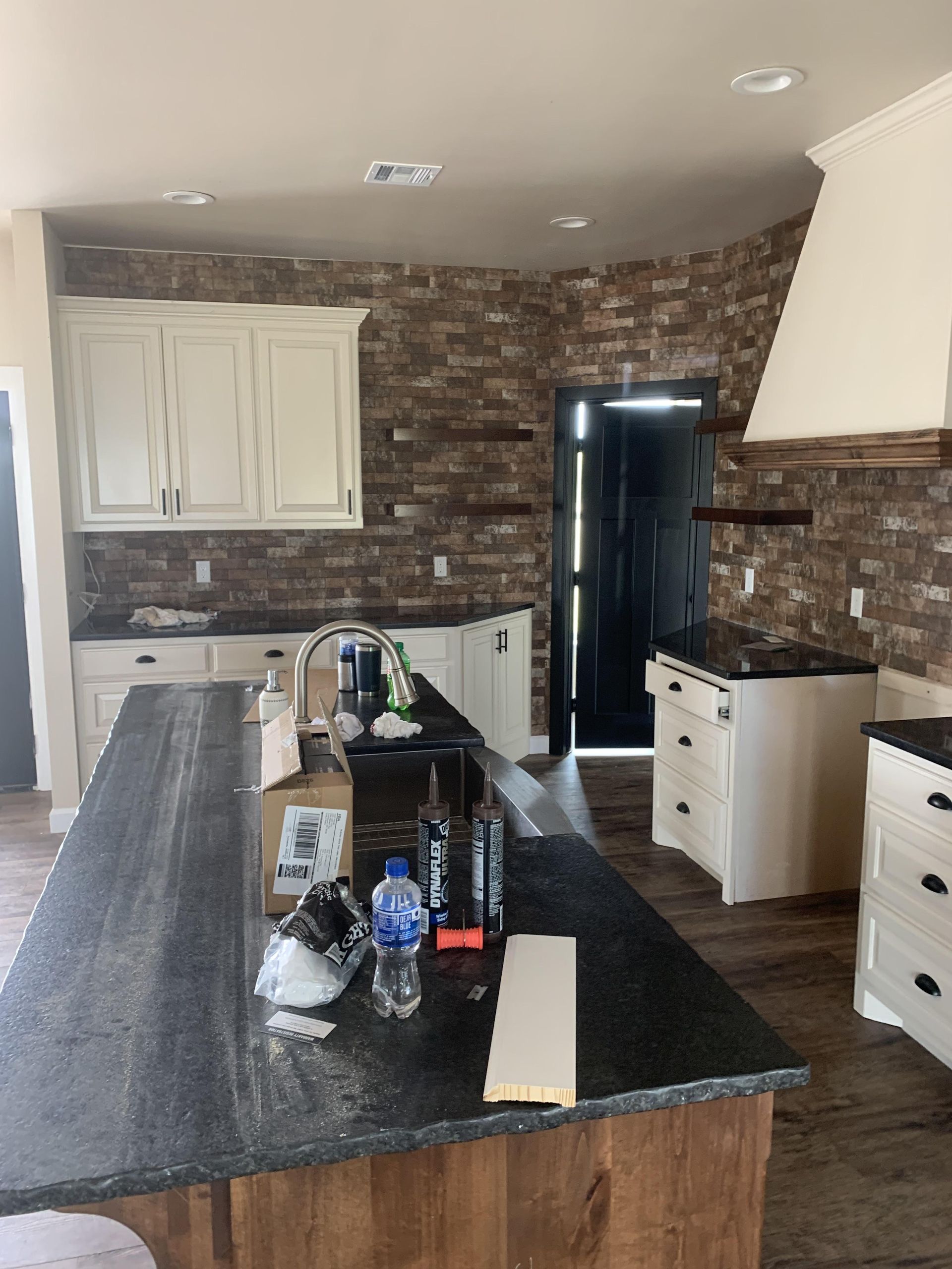 A kitchen with white cabinets and a black counter top