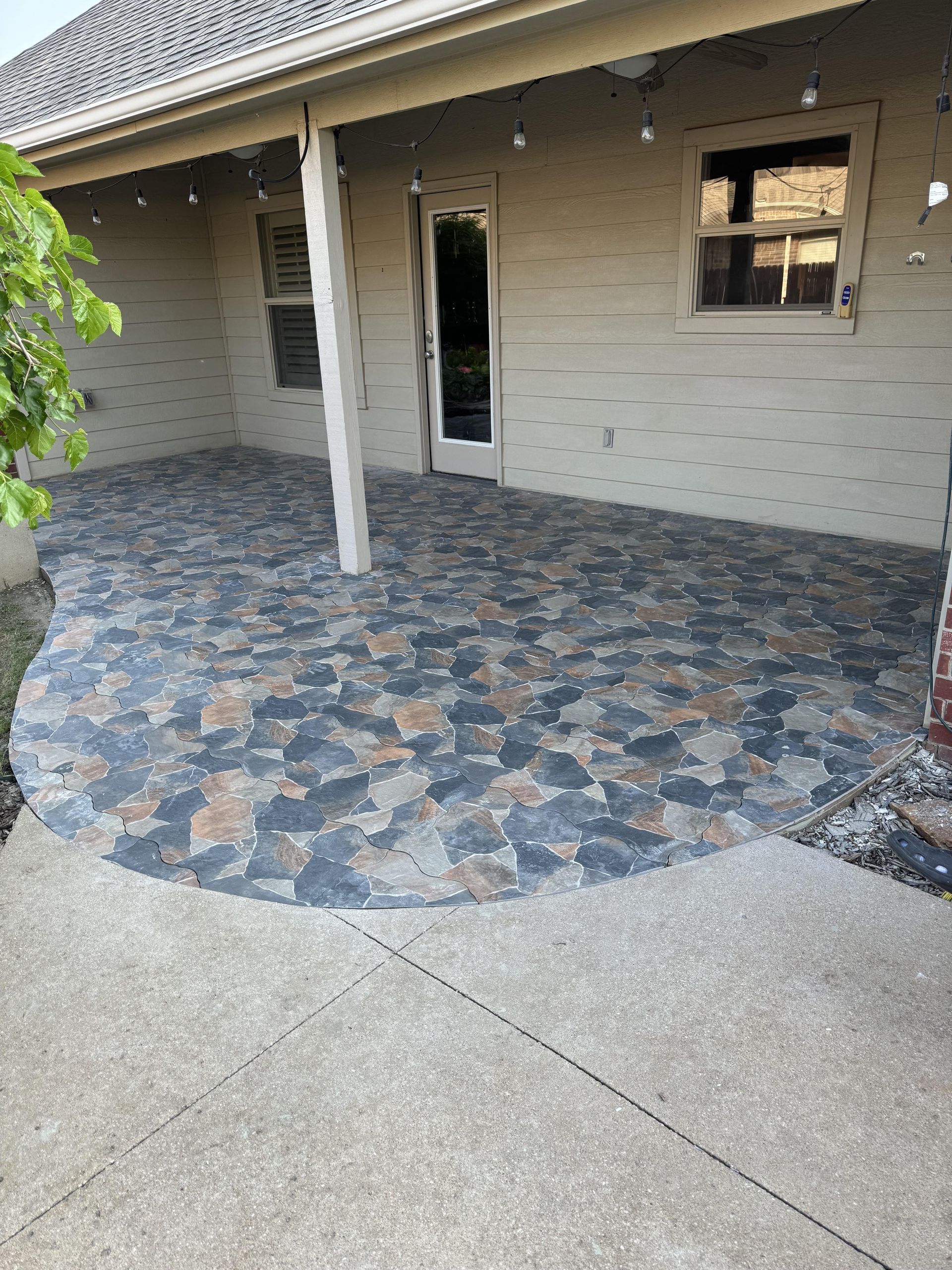 A patio with a brick wall and a sliding glass door.