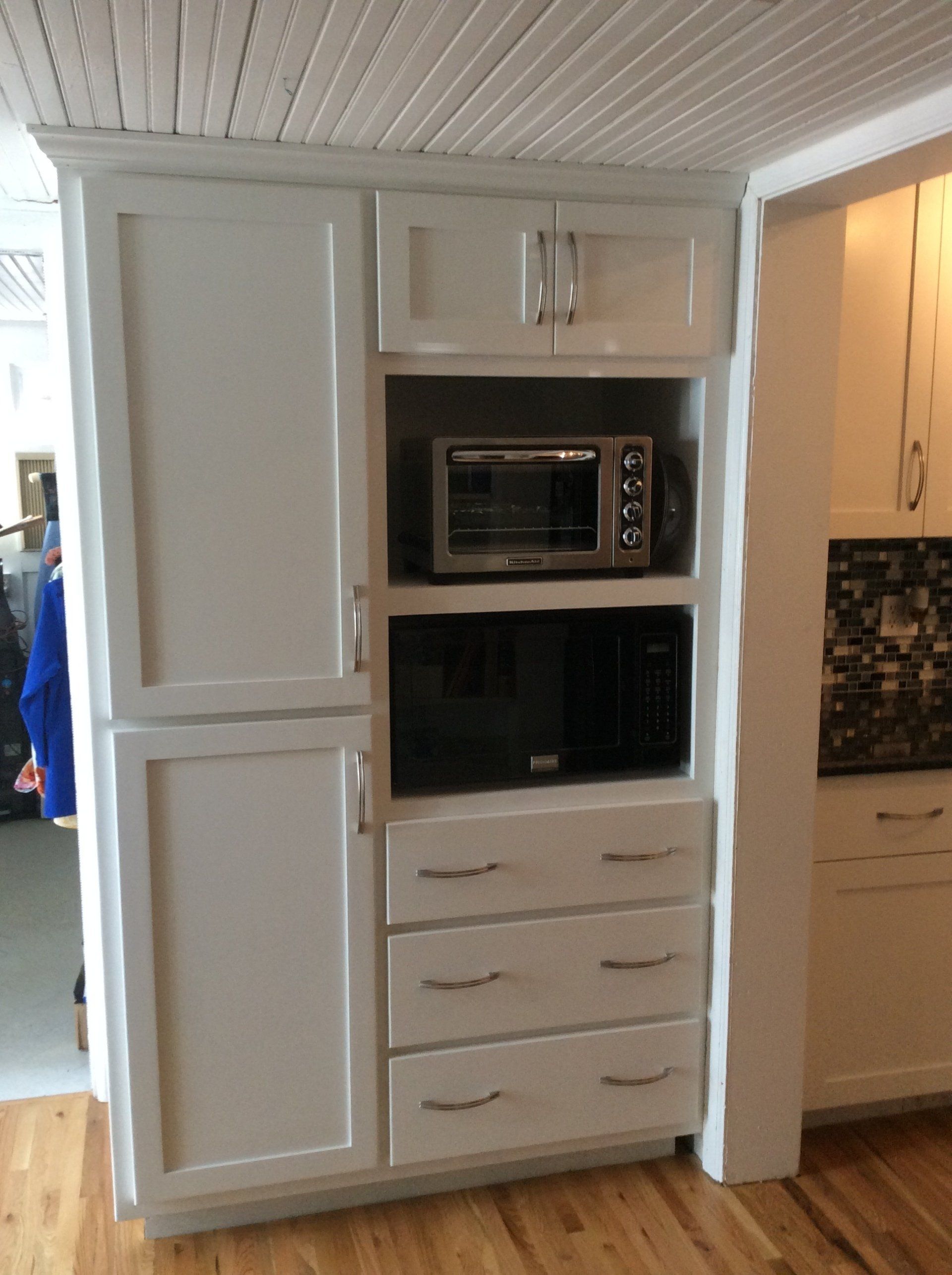A kitchen with white cabinets and a microwave oven