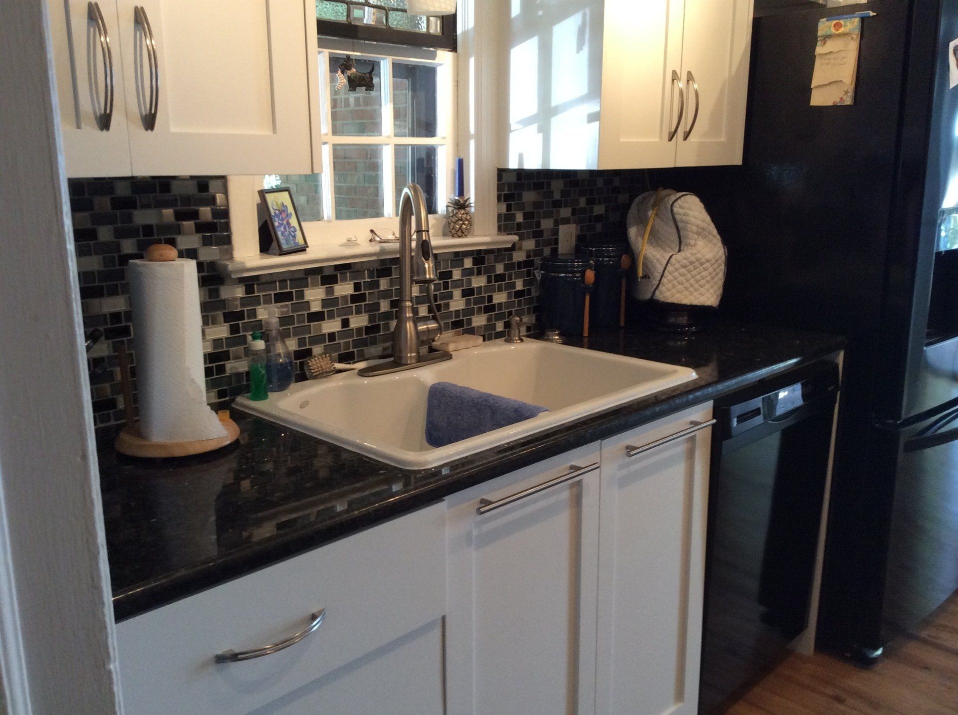 A kitchen with a sink and a black dishwasher