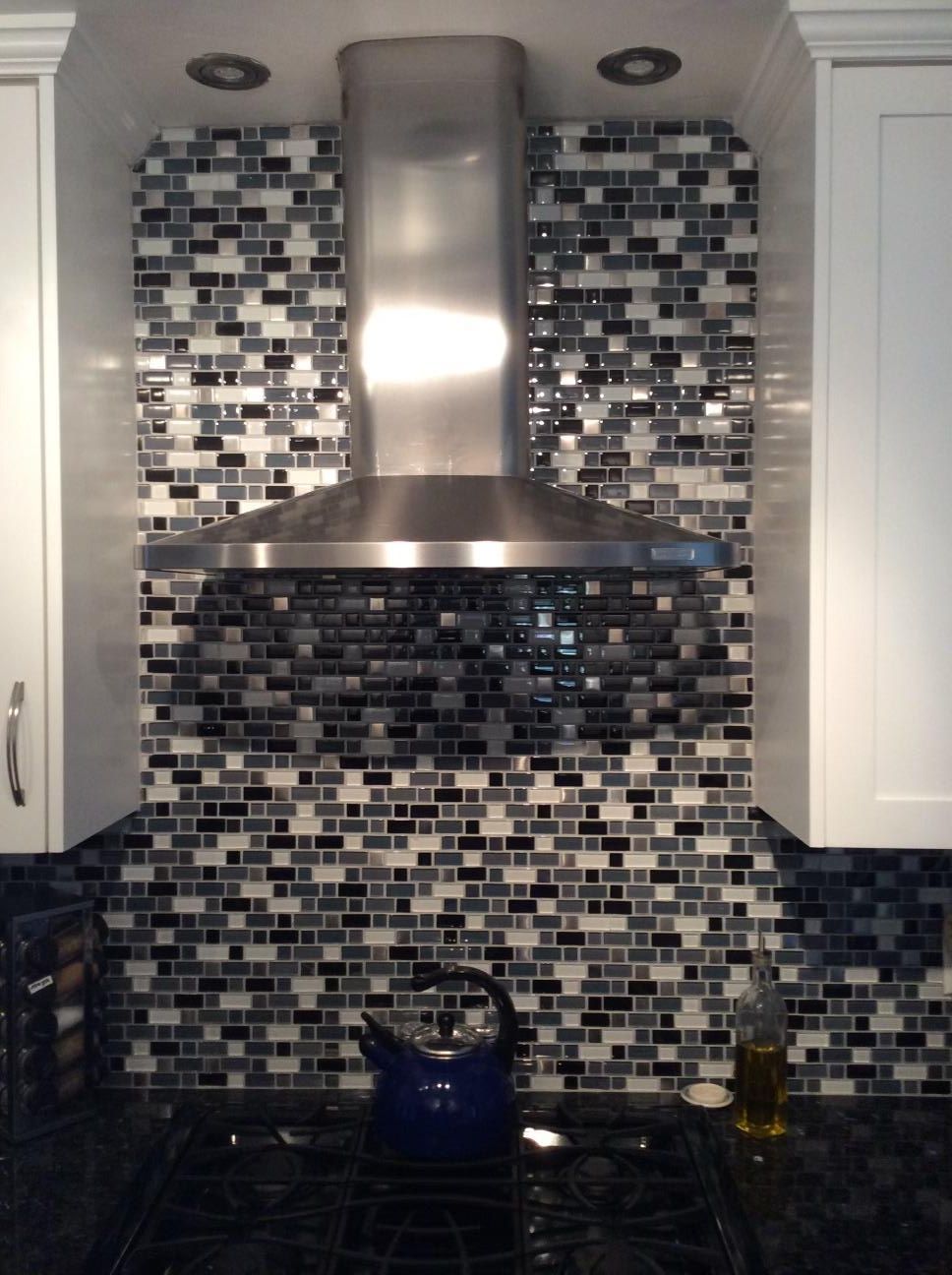 A kitchen with a stove top oven and a stainless steel hood