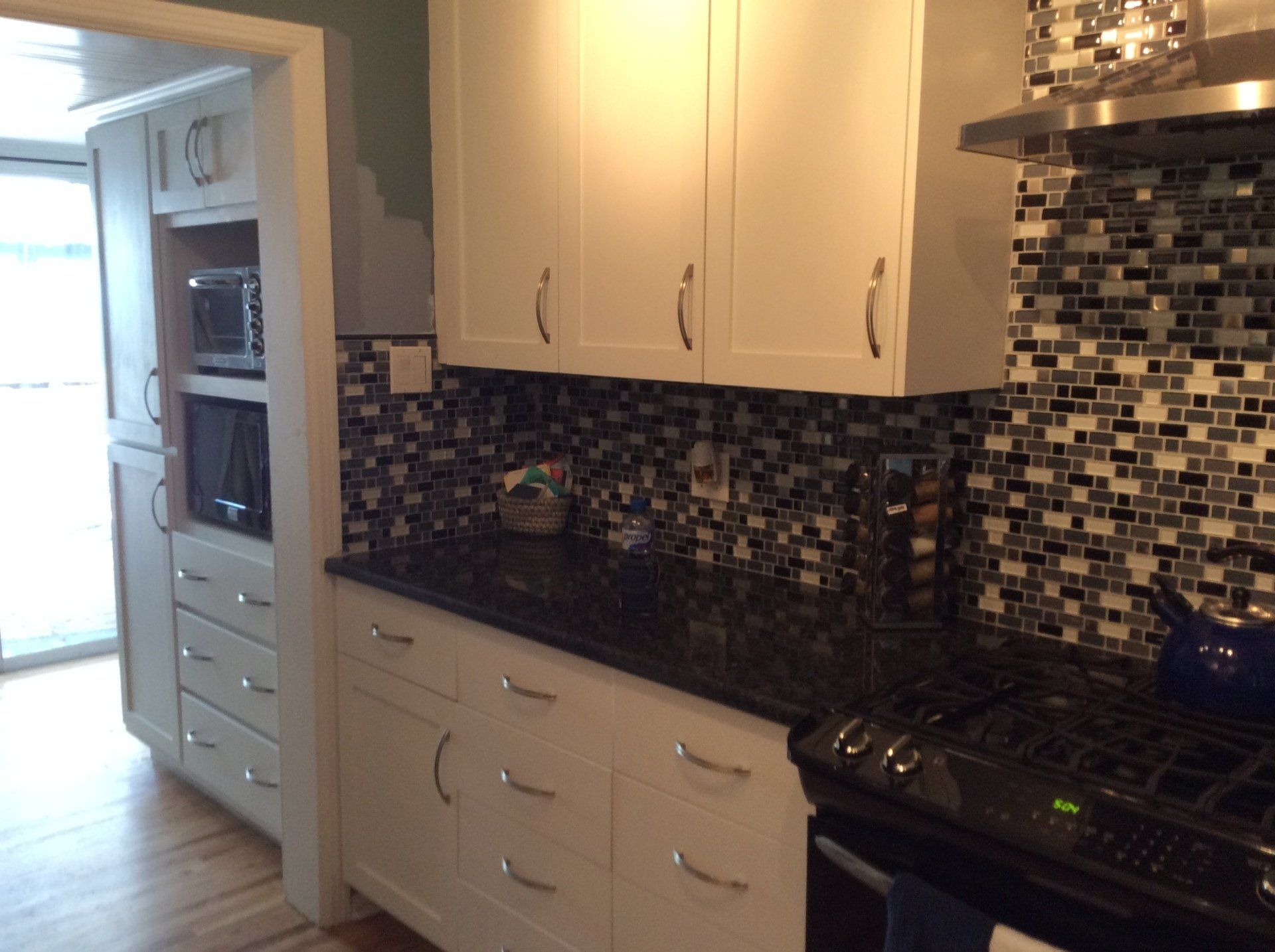 A kitchen with white cabinets and black counter tops