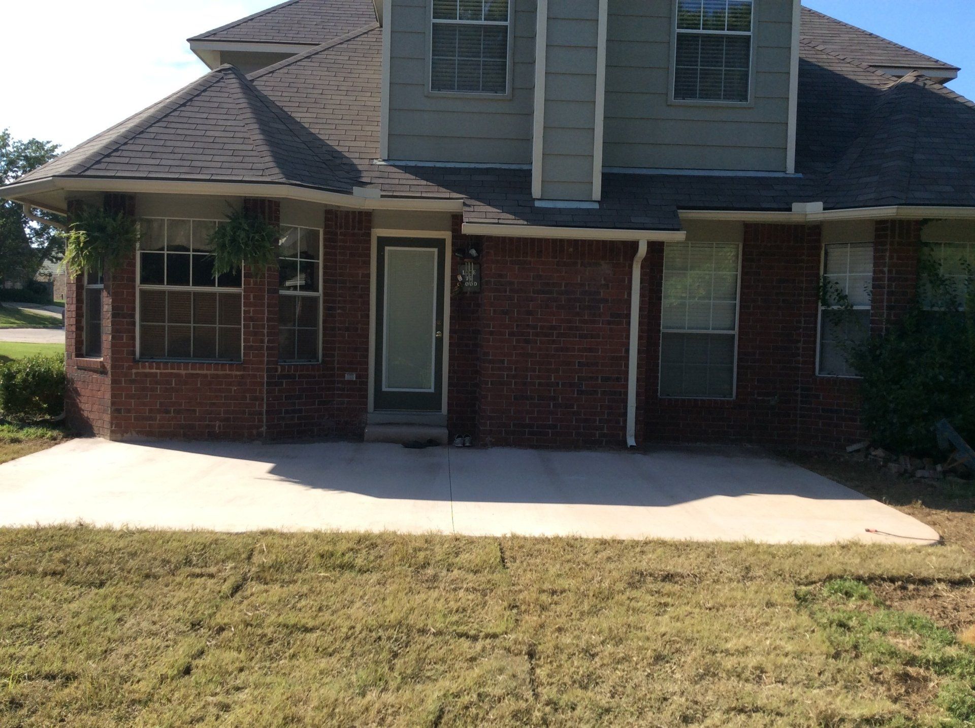 A brick house with a concrete driveway in front of it