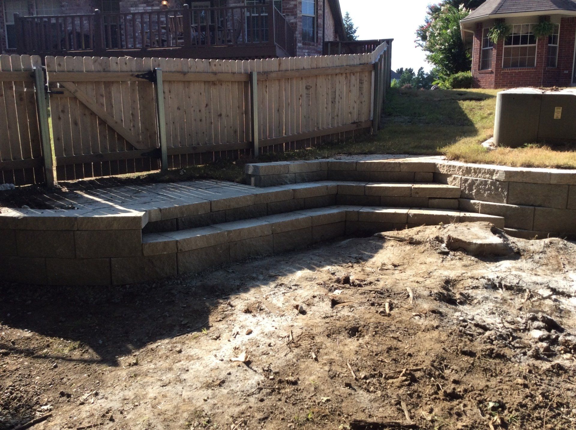 A backyard with stairs and a wooden fence