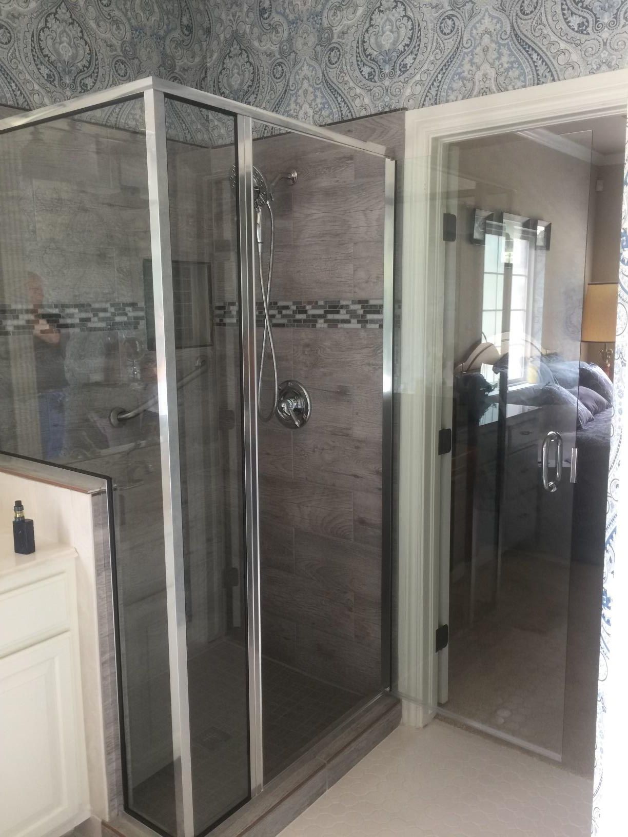 A bathroom with a walk in shower and a glass door.