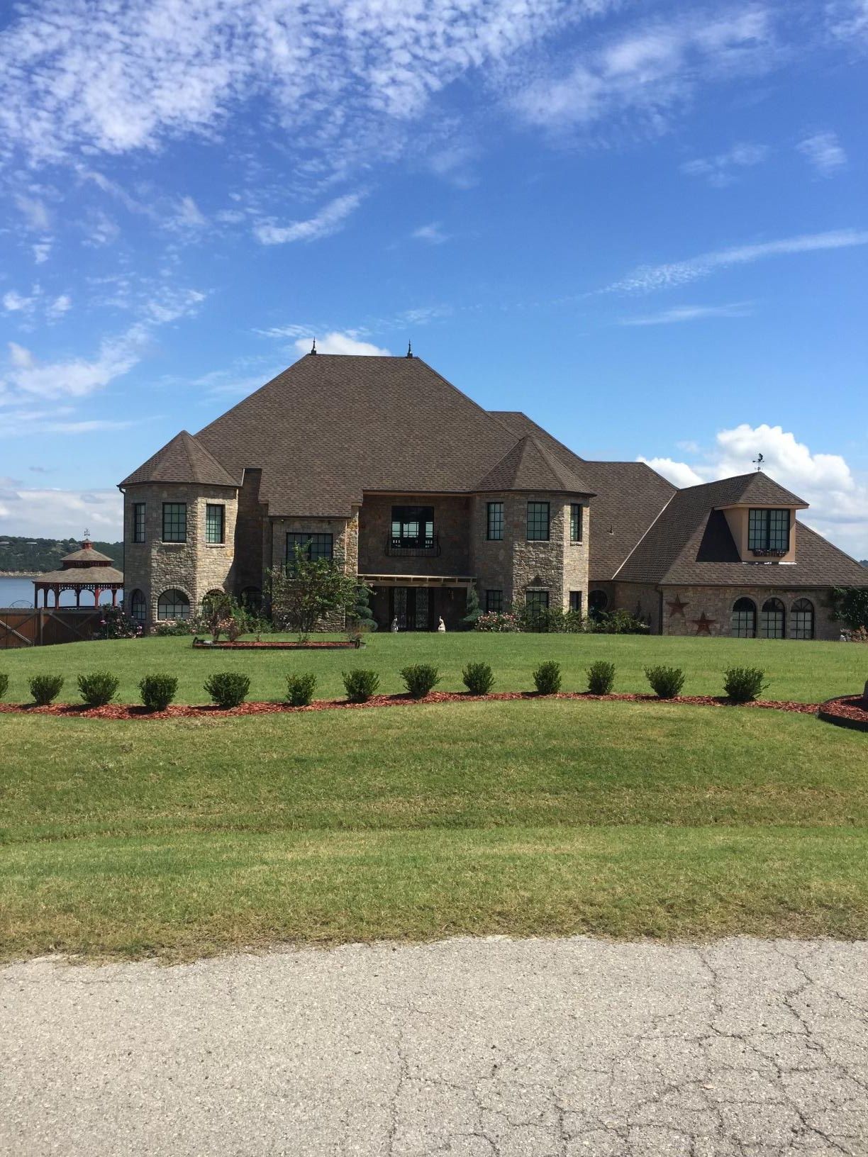 A large house is sitting on top of a lush green field.