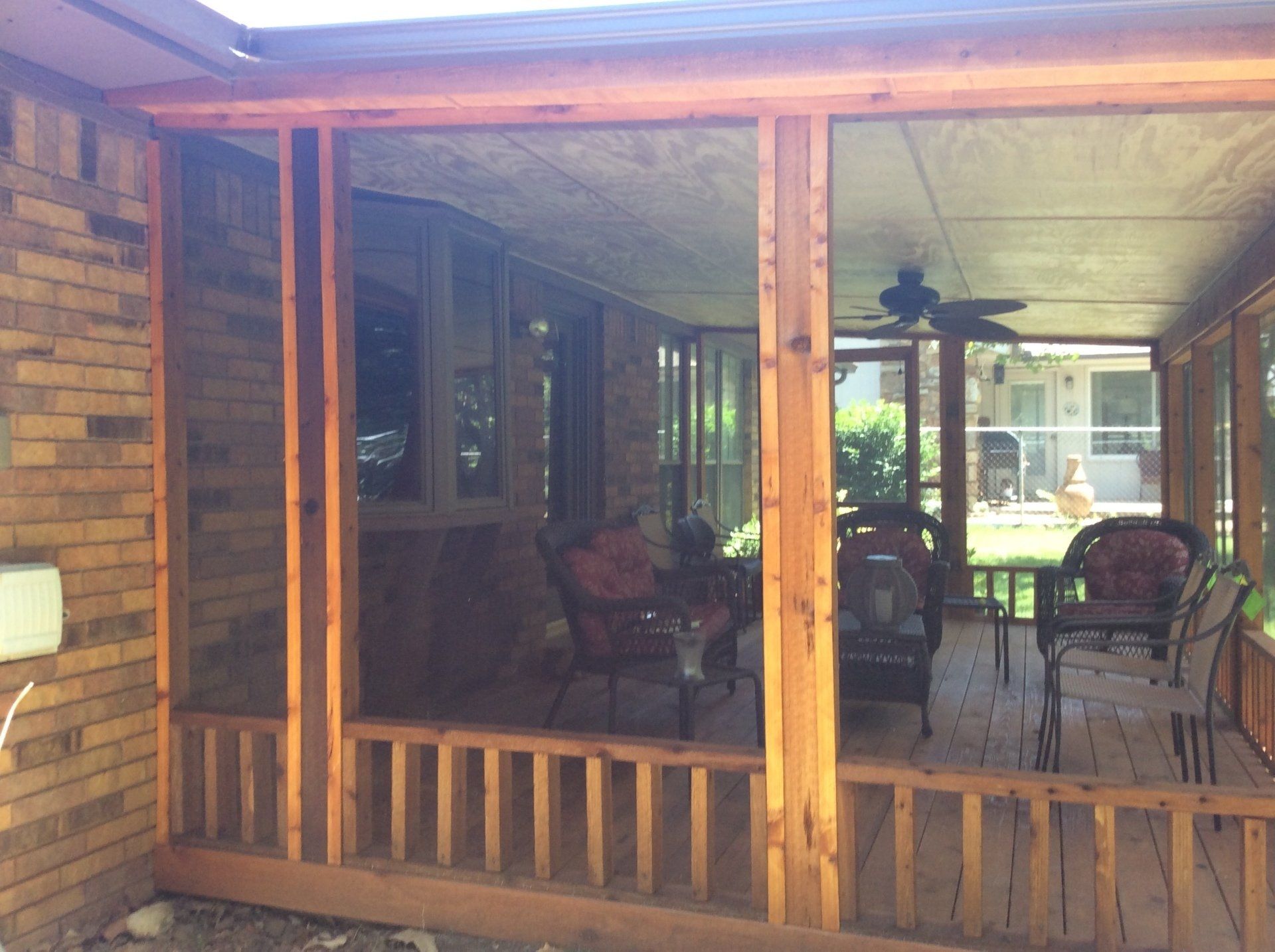 A screened in porch with furniture and a ceiling fan.
