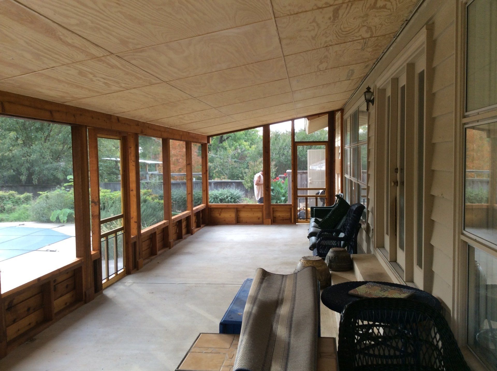 A screened in porch with a swimming pool in the background