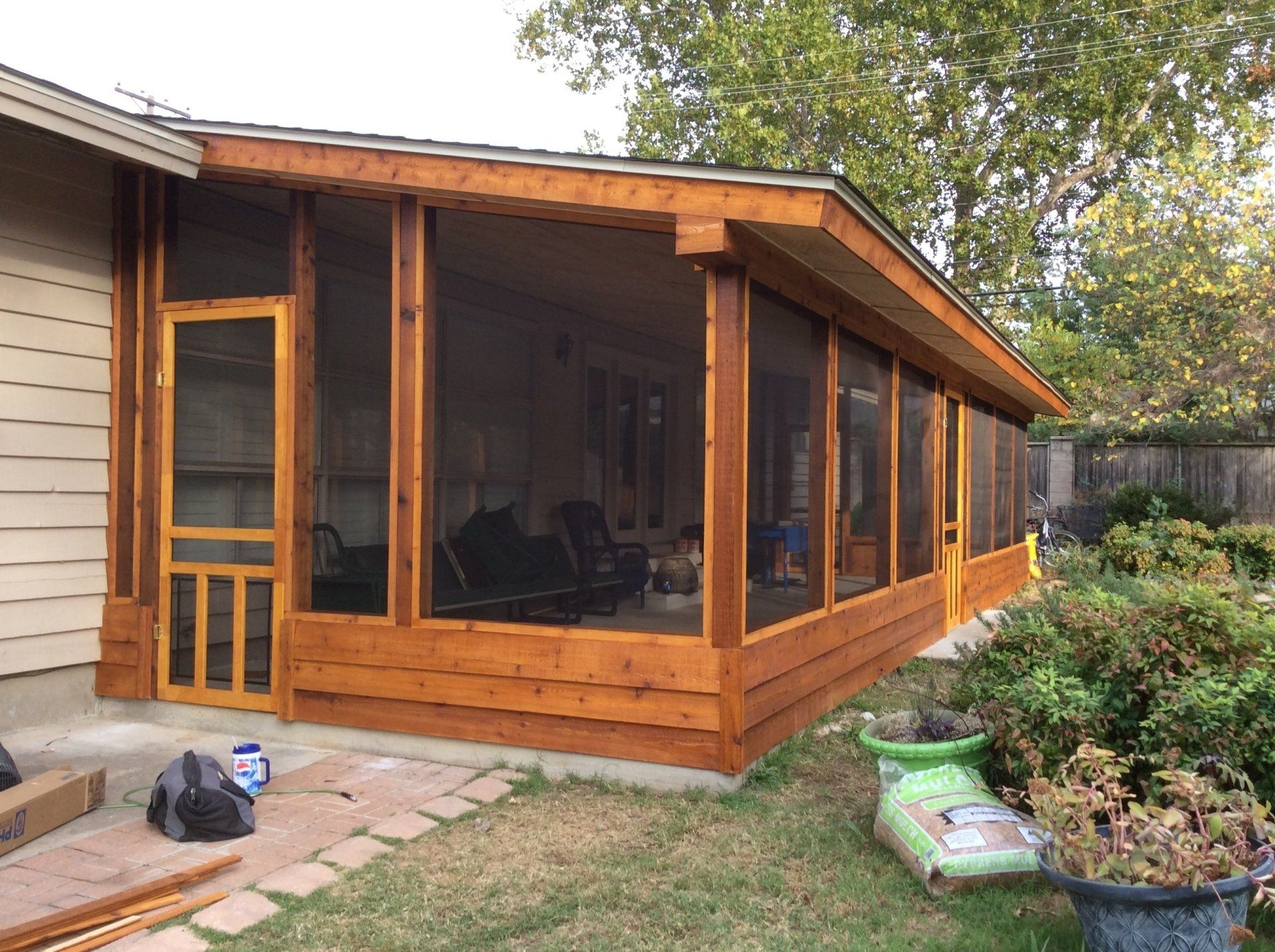 A screened in porch is being built in the backyard of a house.