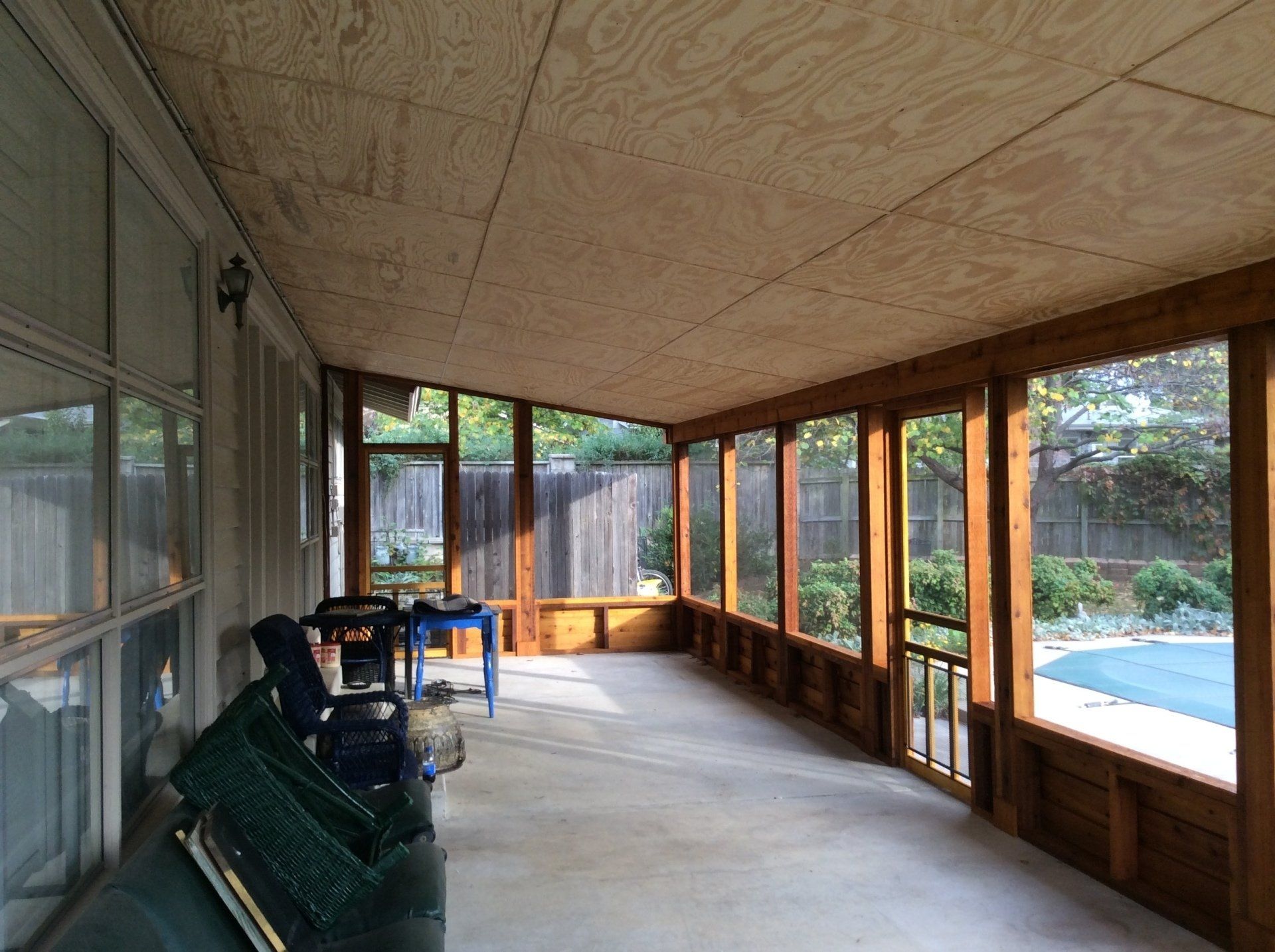 A screened in porch with a pool in the background