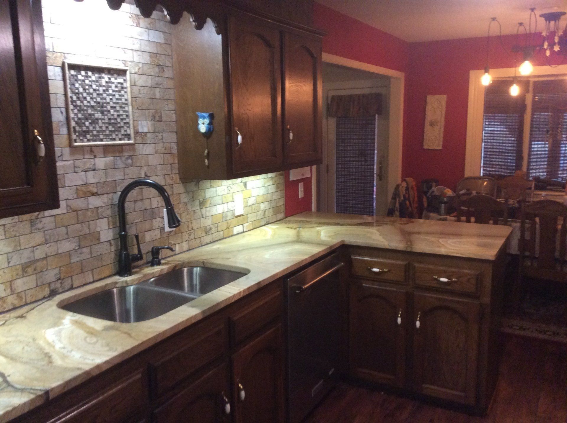 A kitchen with a sink , cabinets , and a dining room in the background.