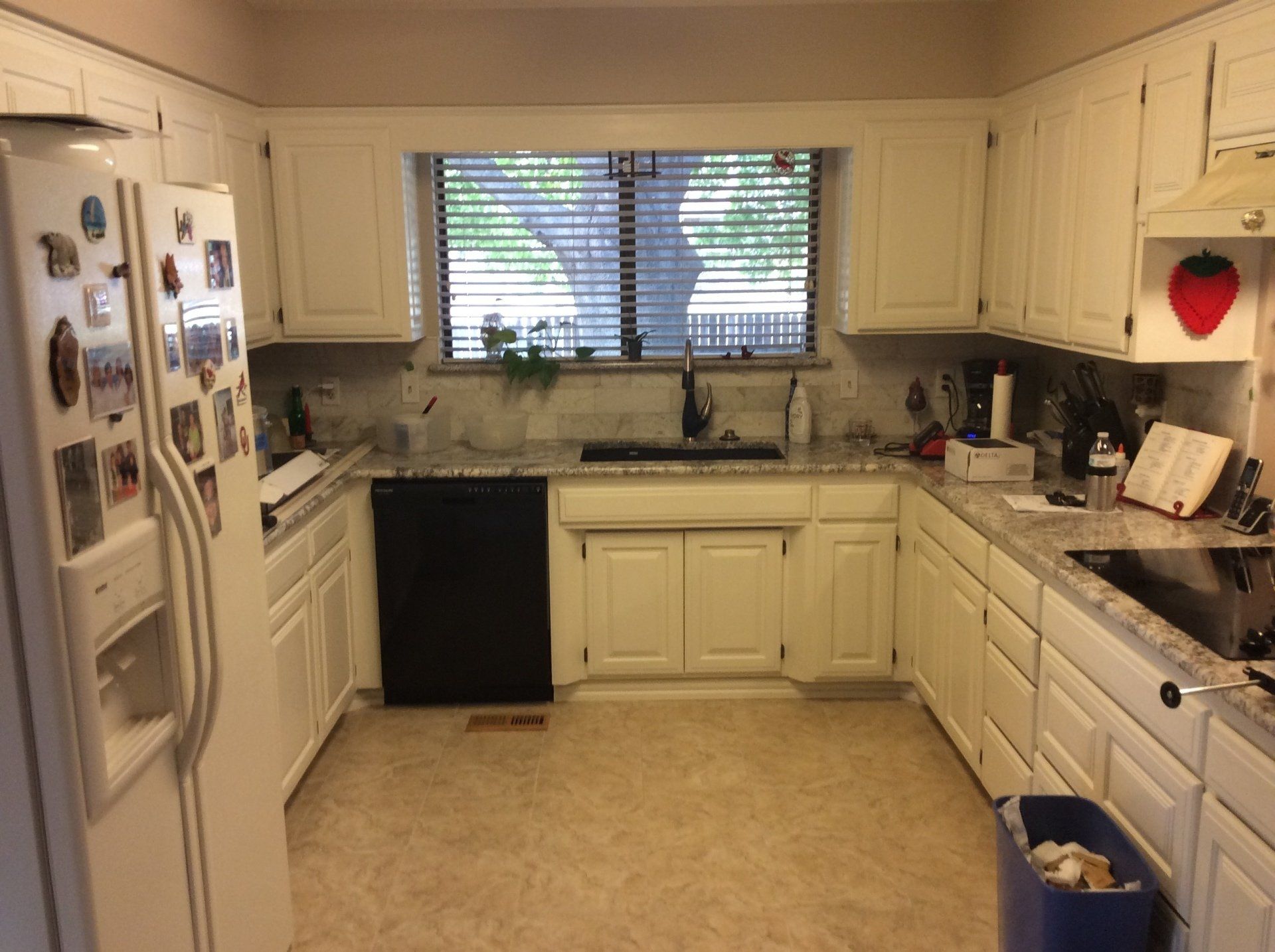 A kitchen with white cabinets and a black dishwasher