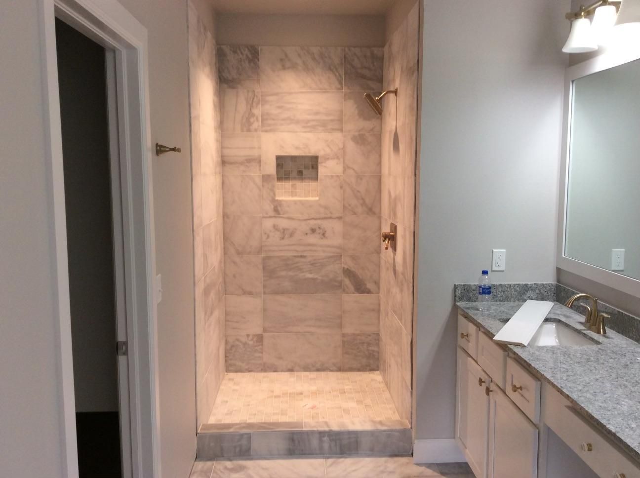 A bathroom with a walk in shower and a sink