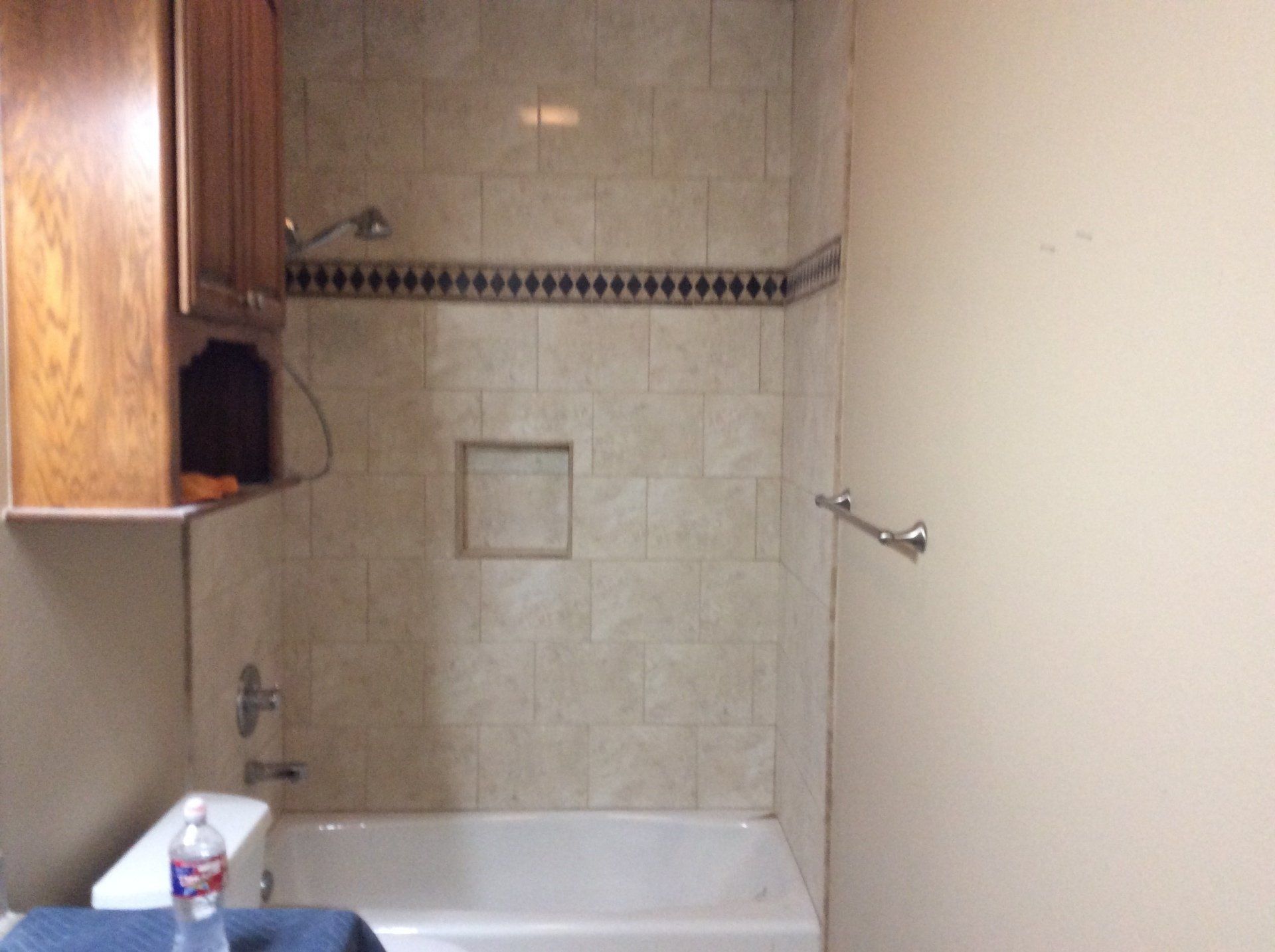 A bathroom with a bathtub toilet and a bottle of aquafina water