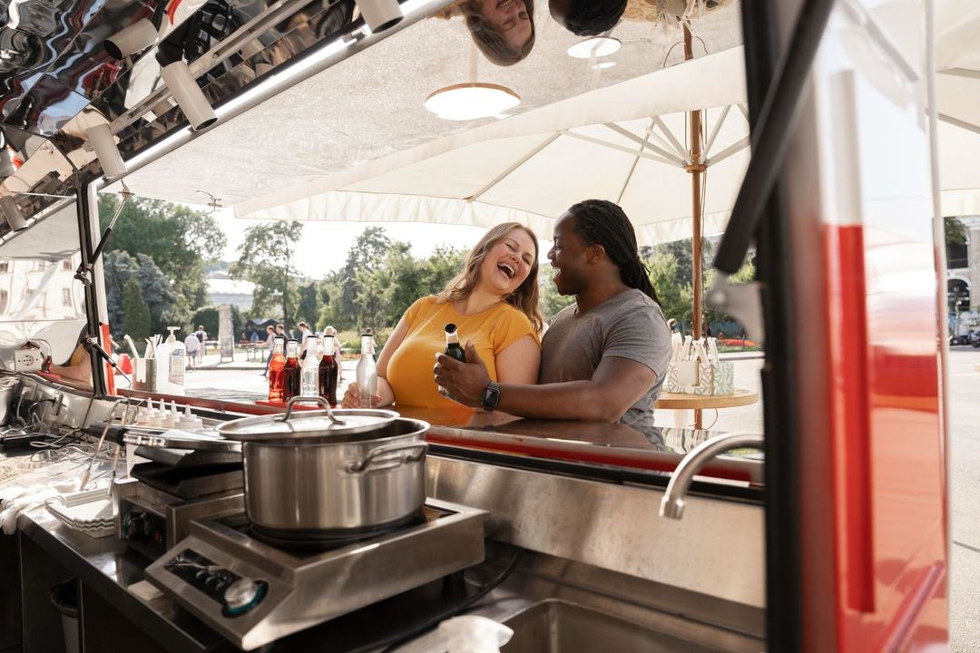 A man and a woman are sitting at a counter in a food truck.