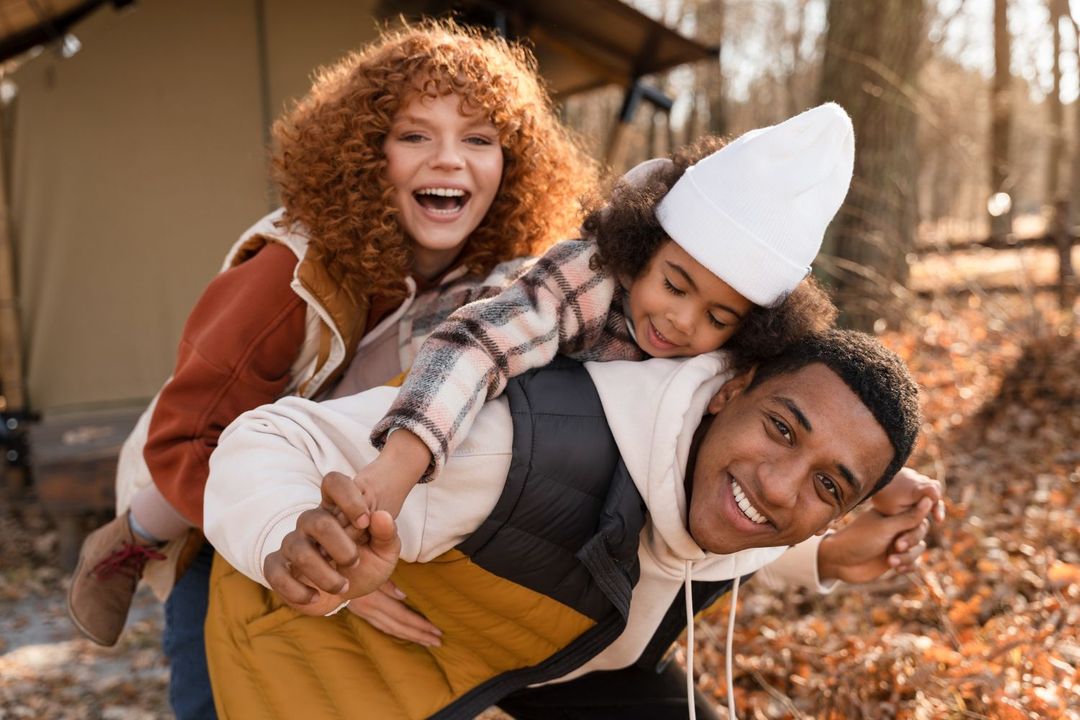 A man is carrying a woman and a child on his back.