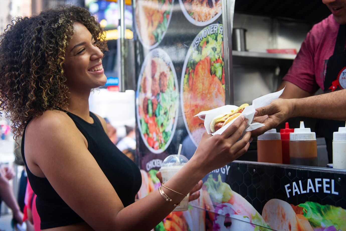 A woman is getting a falafel sandwich from a food truck.