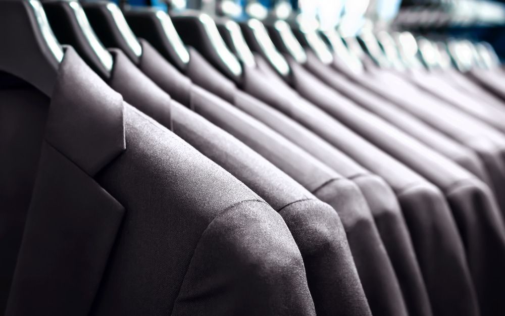 A Row Of Custom Suits Hanging On A Rack In A Store  — Gympie Embroidery Services In Southside, QLD