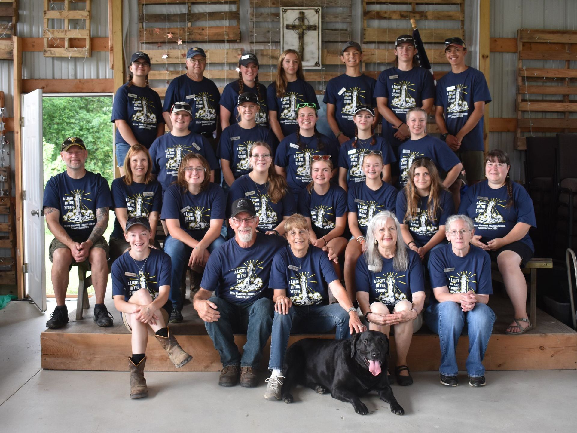 A group of people posing for a picture with a black dog