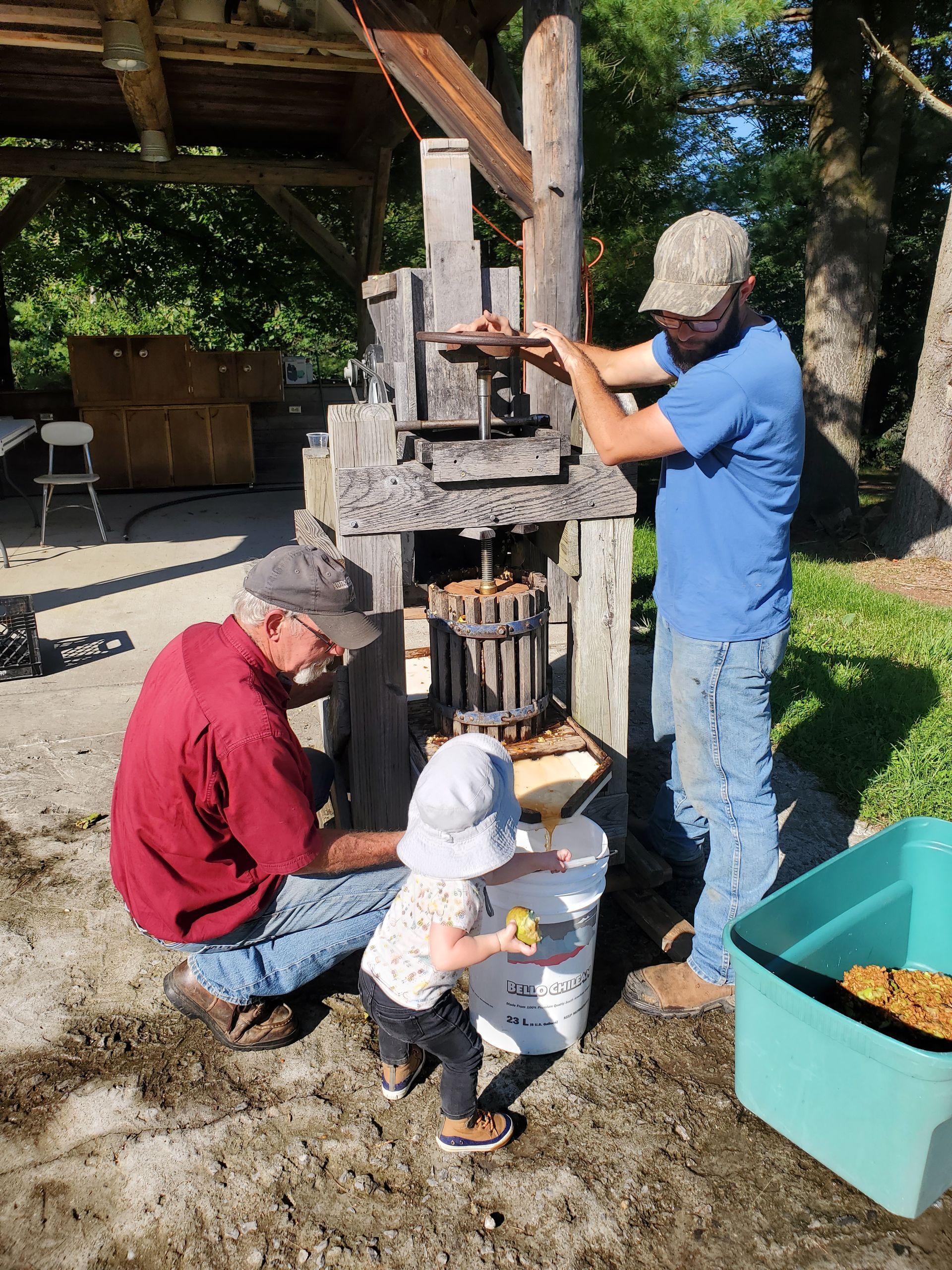 Two men and a little girl are working on a machine.