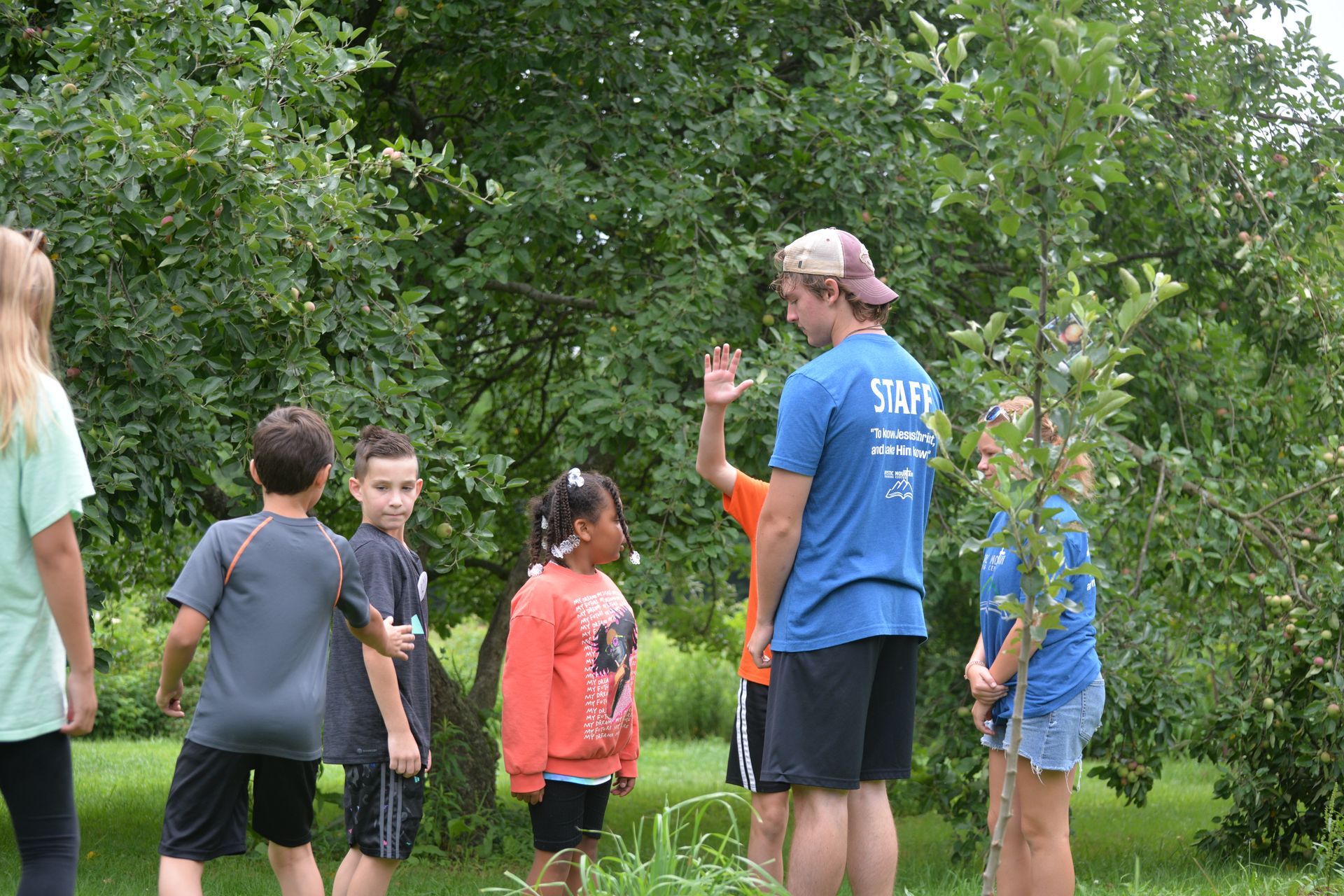 A group of children are standing in front of a tree.